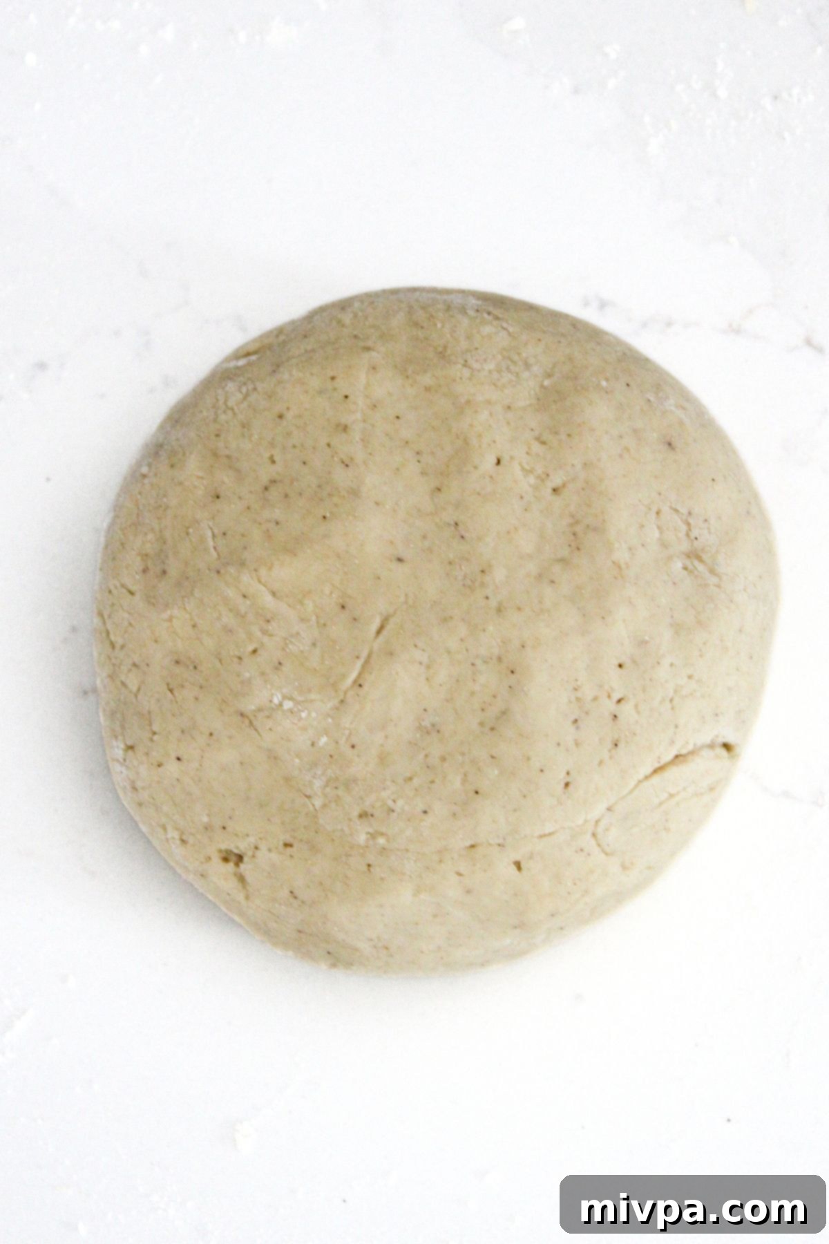 A big ball of gluten-free pretzel dough resting in a bowl, covered for rising.