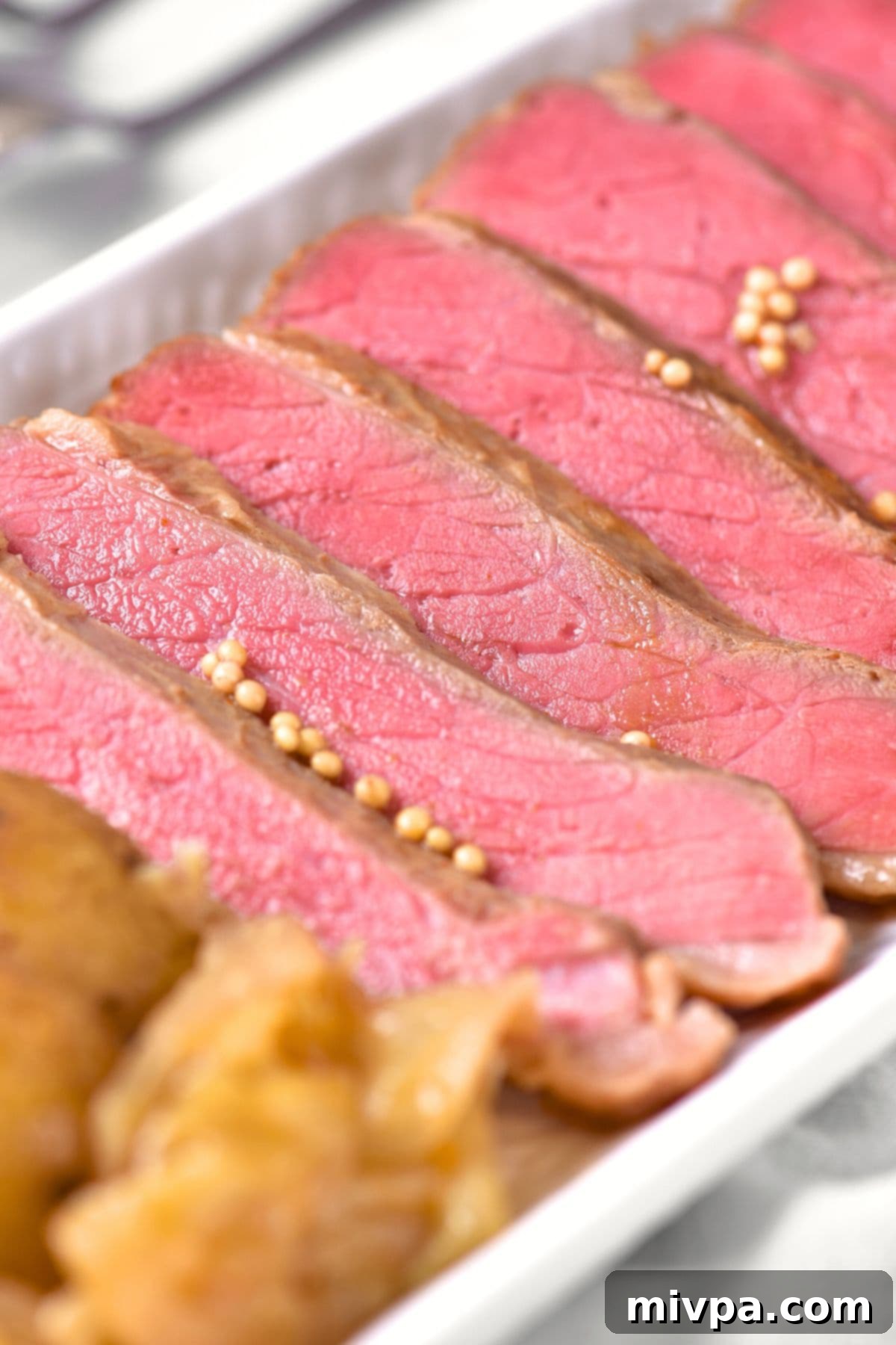 Sliced corned beef and cabbage on a white plate, garnished and ready to serve.