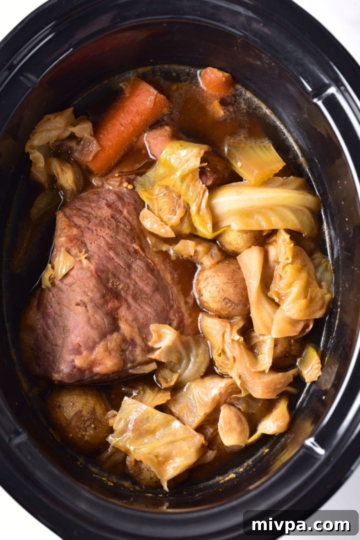 The finished corned beef and cabbage, resting in the slow cooker with the cooking liquid.