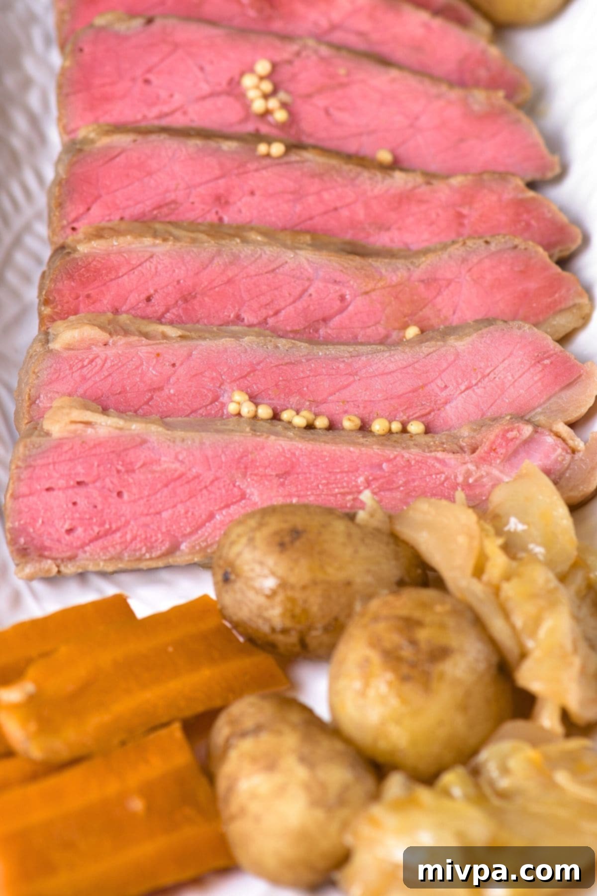 Platter of sliced corned beef with tender vegetables, ready for serving.