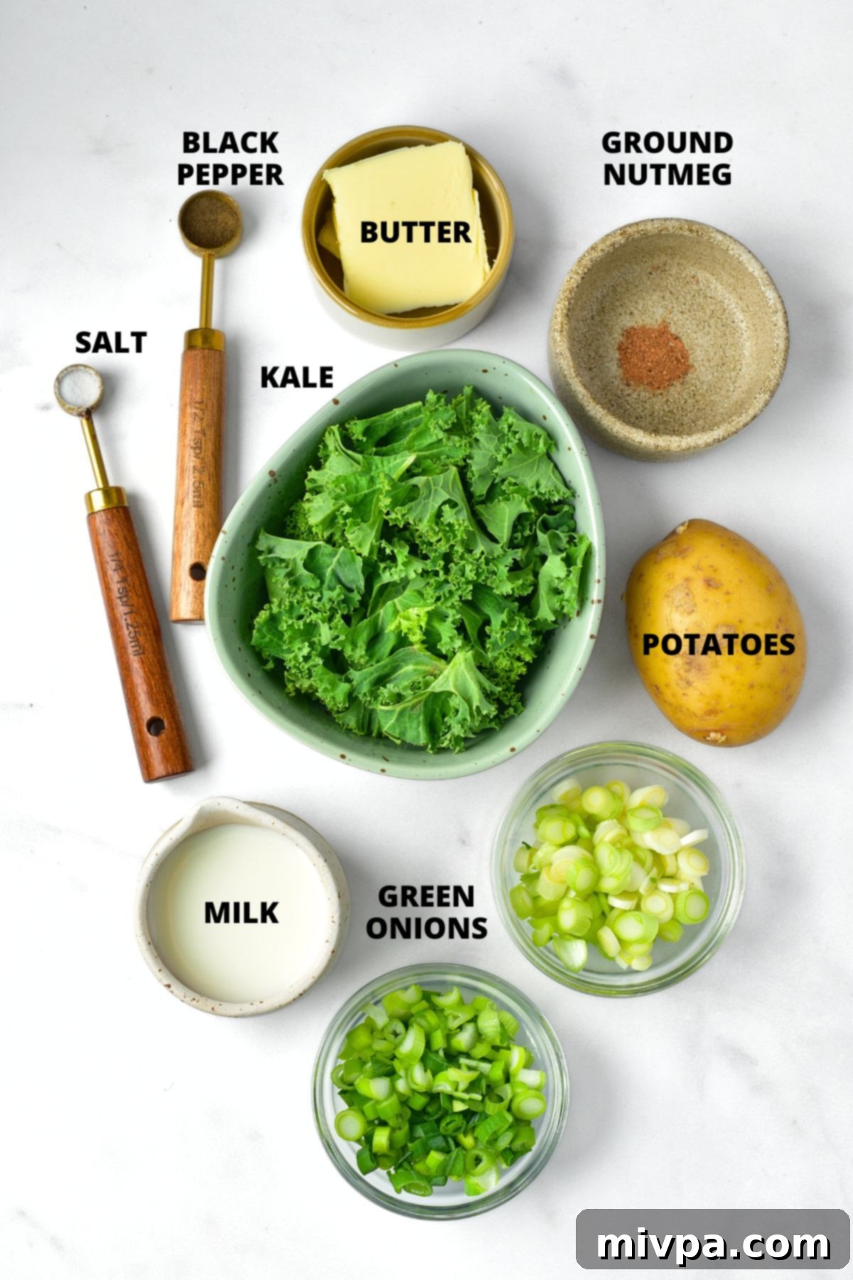 Colcannon Recipe (Irish Mashed Potatoes) Ingredients Ingredients for Irish colcannon recipe including potatoes, kale, green onions, milk, butter, and spices, laid out on a white board.