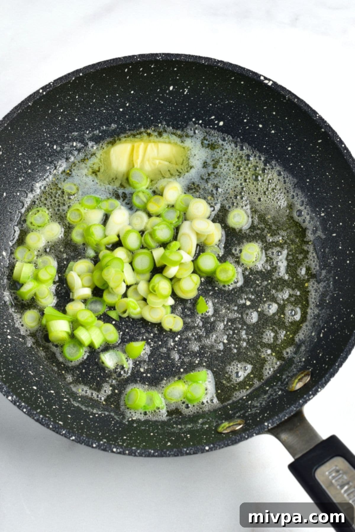 Sautéing Green Onions for Colcannon Sautéing chopped green onions in melted butter in a skillet