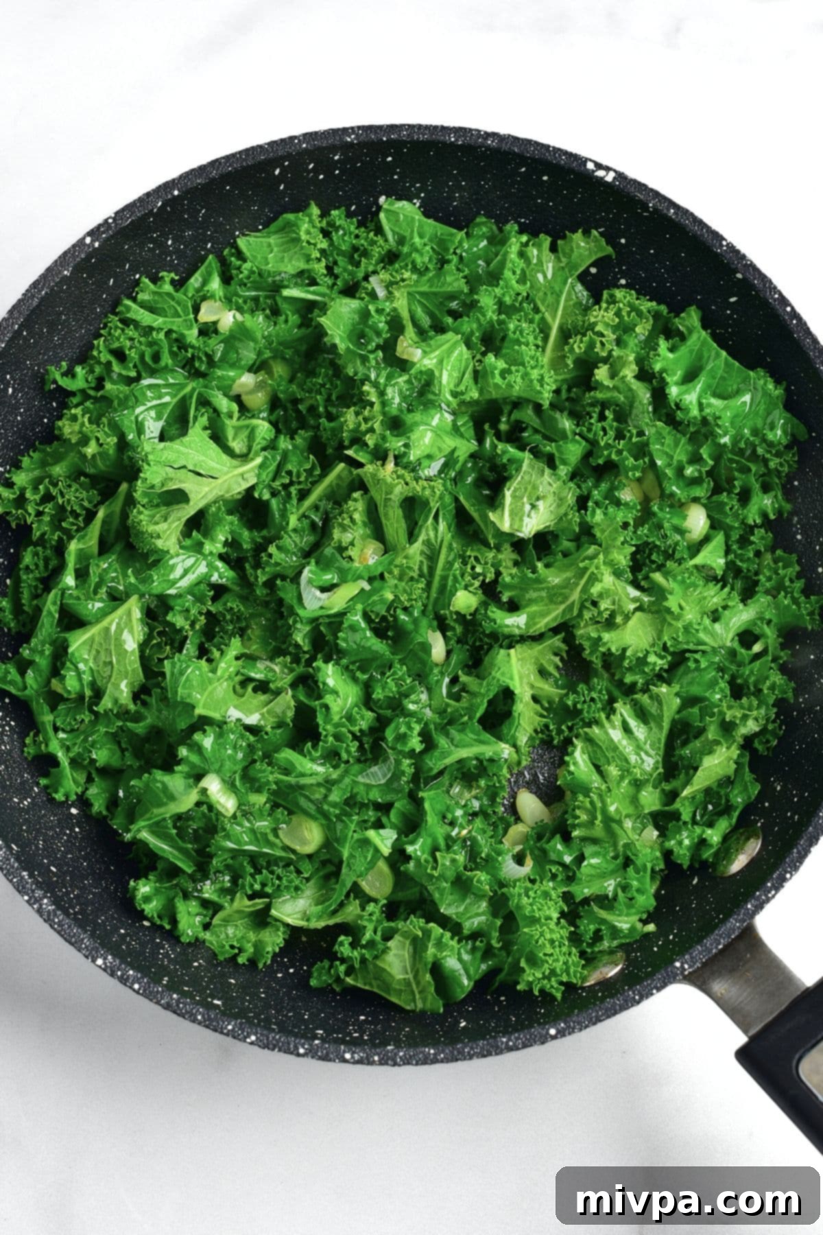 Cooking Kale for Irish Colcannon Cooking kale leaves in a skillet with green onions