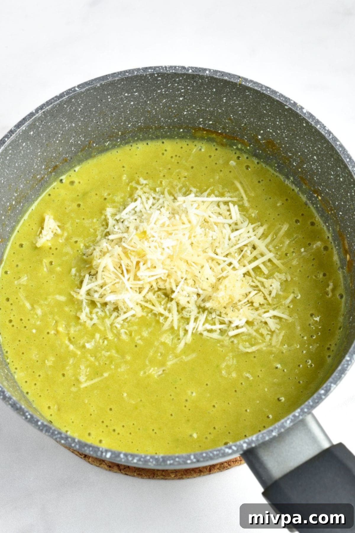 Shredded cheese on top of green soup
