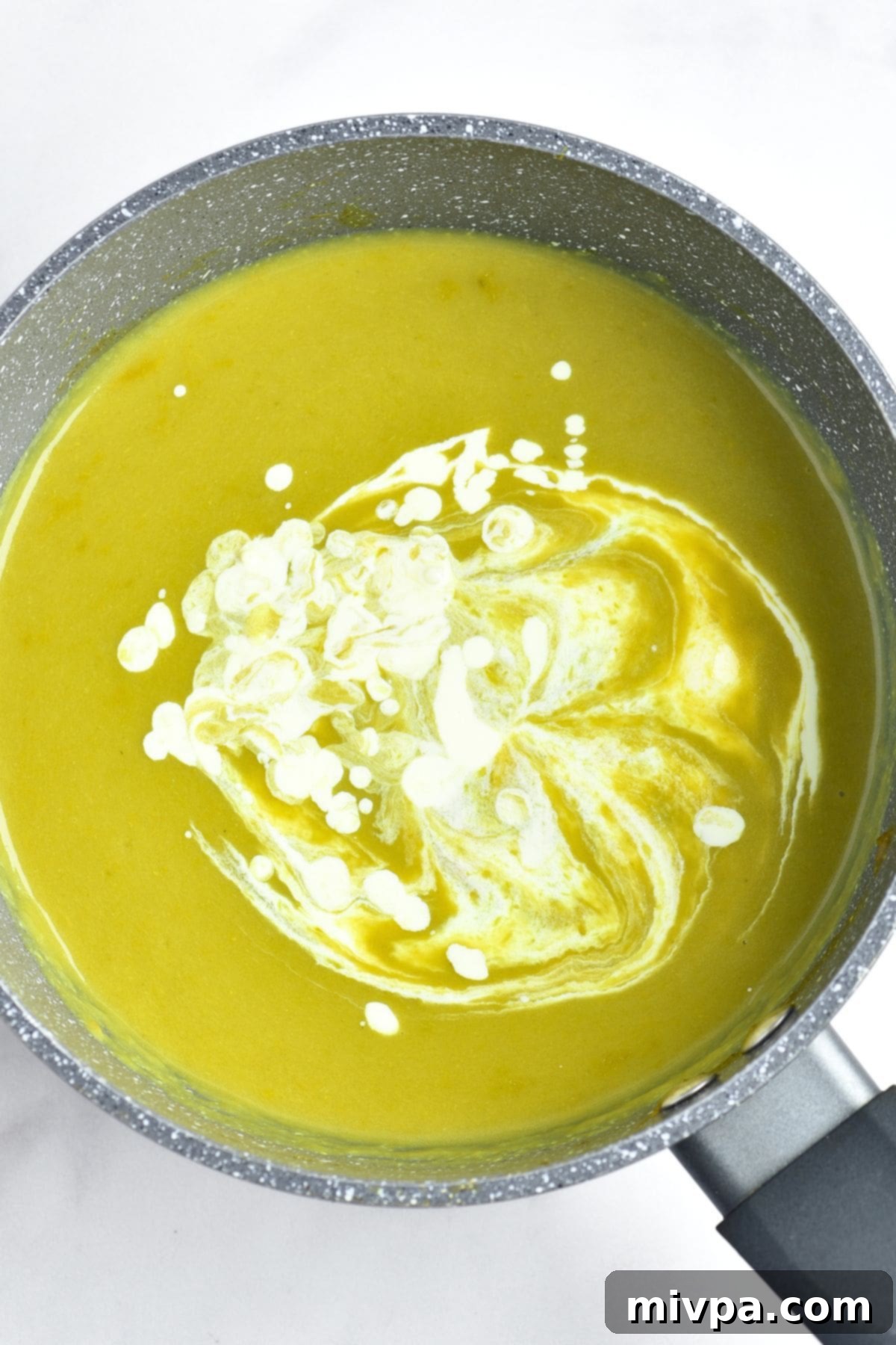 Cream drizzled in a pot of asparagus soup