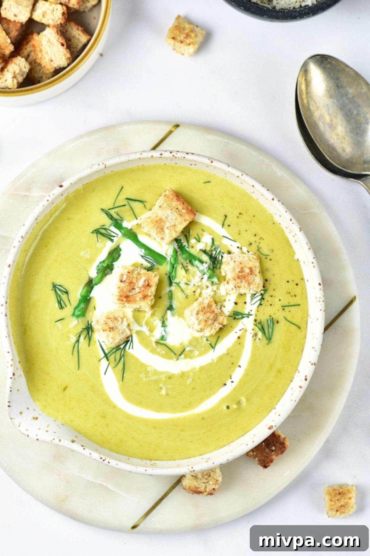 A bowl of asparagus potato soup topped with croutons