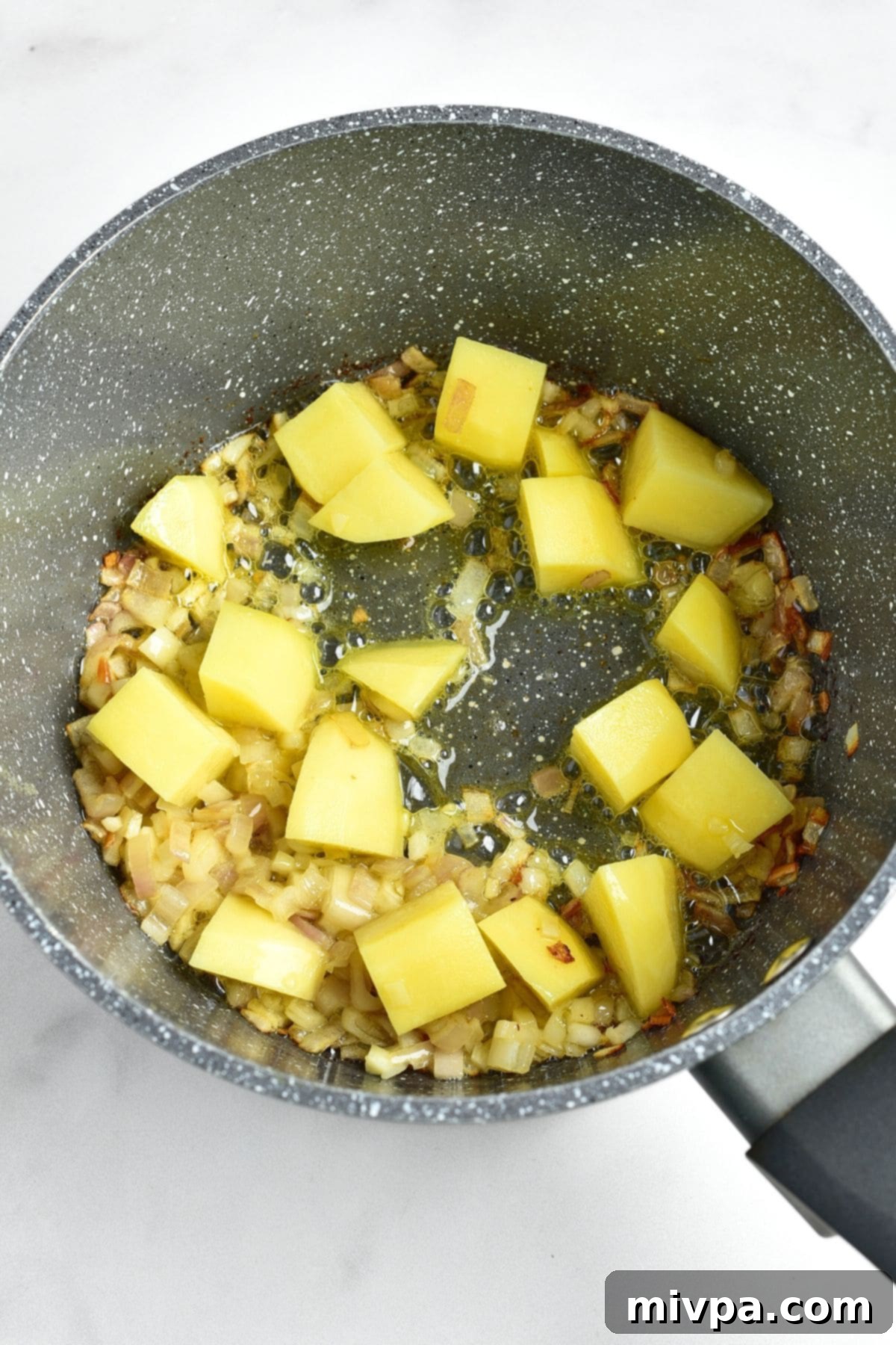 Cooking cubed potatoes and shallots in saucepan