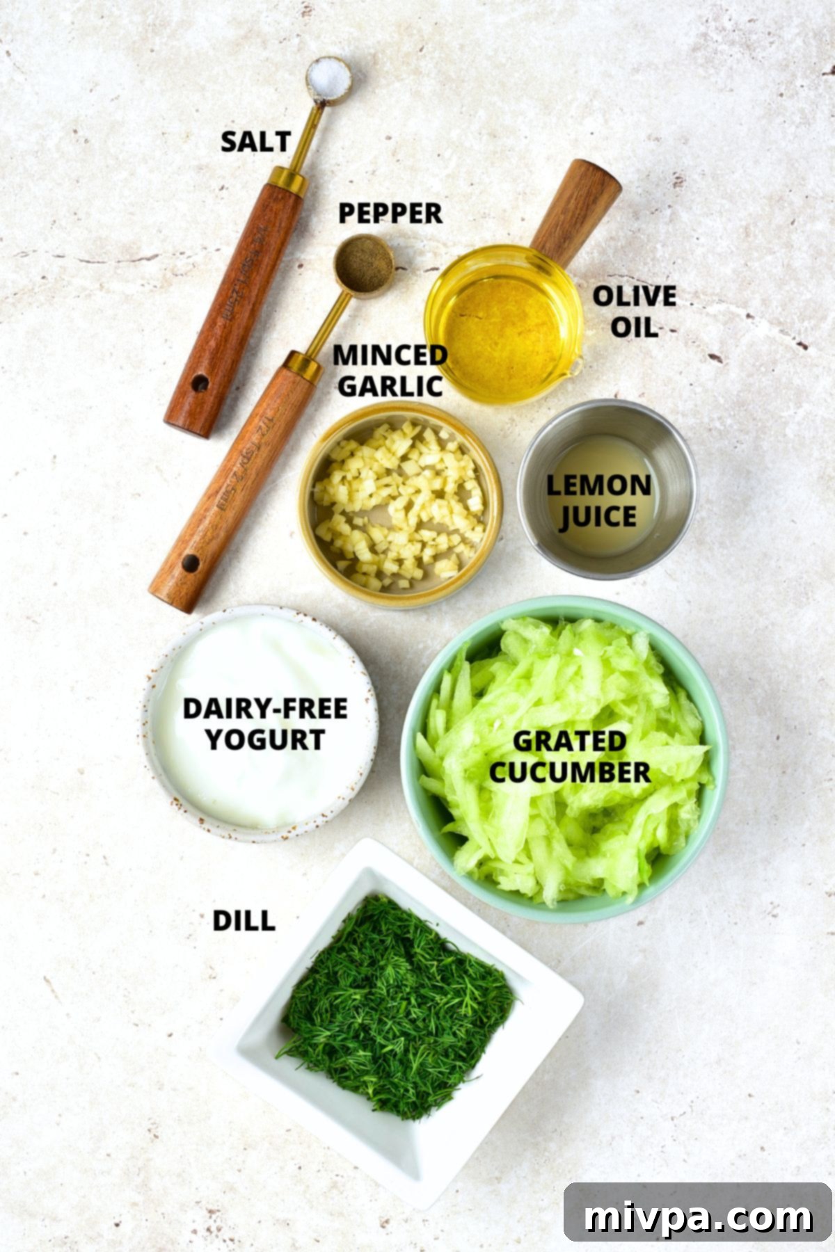 All the ingredients for dairy-free tzatziki recipe beautifully laid out on a white board.