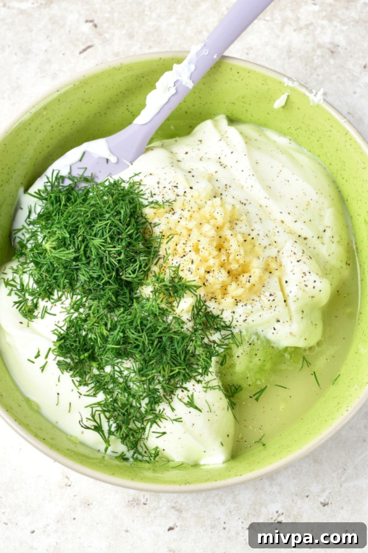 All tzatziki ingredients: yogurt, minced garlic, fresh dill, lemon juice, and grated cucumber, gathered in a bowl before mixing.