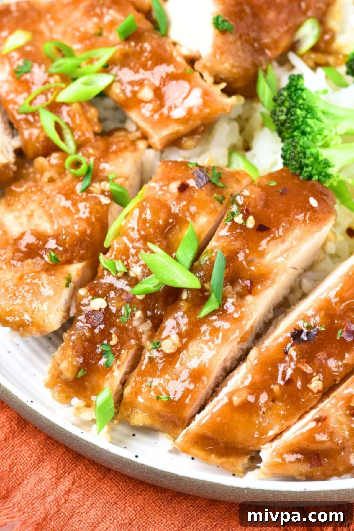 Honey Garlic Chicken (Gluten-Free, Dairy-Free) A plate of sliced honey garlic chicken topped with green onions, showcasing a delicious meal.