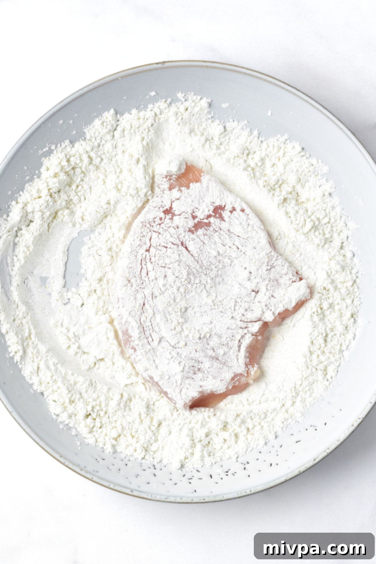 Honey Garlic Soy Chicken Coating chicken fillets evenly in a cornstarch mixture for a crispy crust.