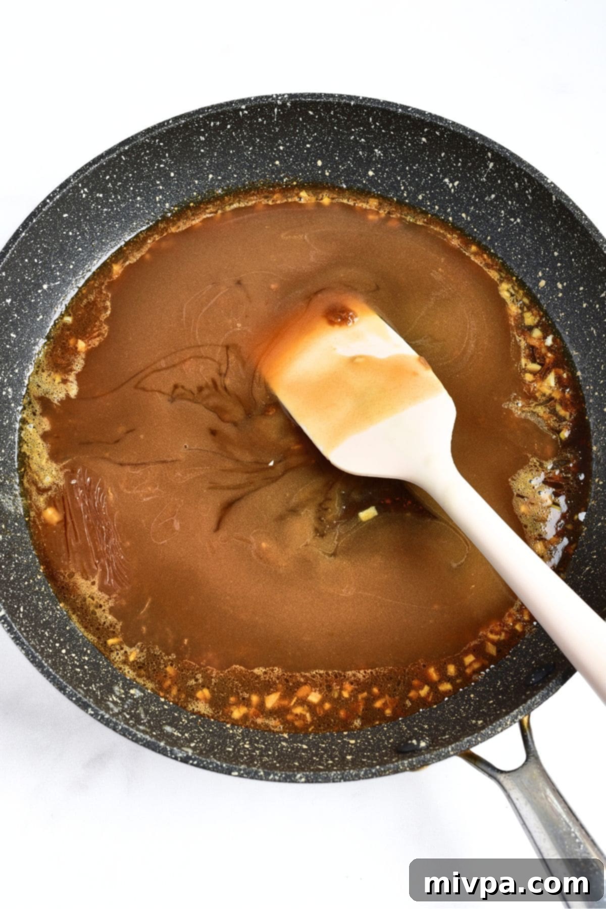 Gluten-Free Honey Garlic Sauce Cooking gluten-free honey garlic sauce in skillet, letting it thicken.