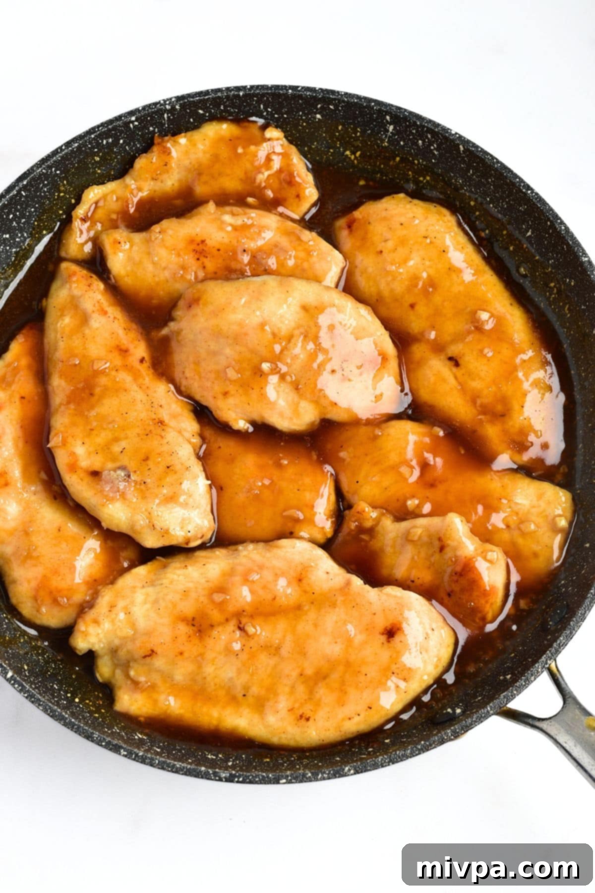 Garlic and Honey Chicken Recipe Chicken fillets coating in the rich brown sauce in skillet.