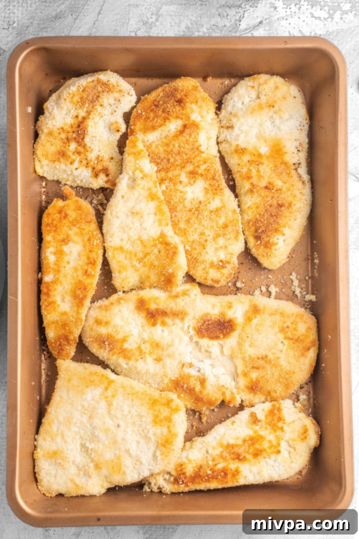 A baking sheet filled with freshly baked gluten-free breaded chicken cutlets, golden and crispy, ready to be served as a wholesome family meal.