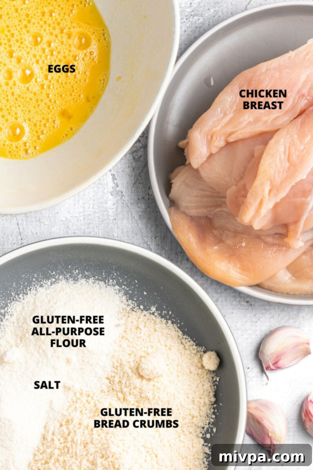 All the necessary ingredients for gluten-free breaded chicken recipe, neatly laid out on a wooden board, showcasing their freshness and simplicity.