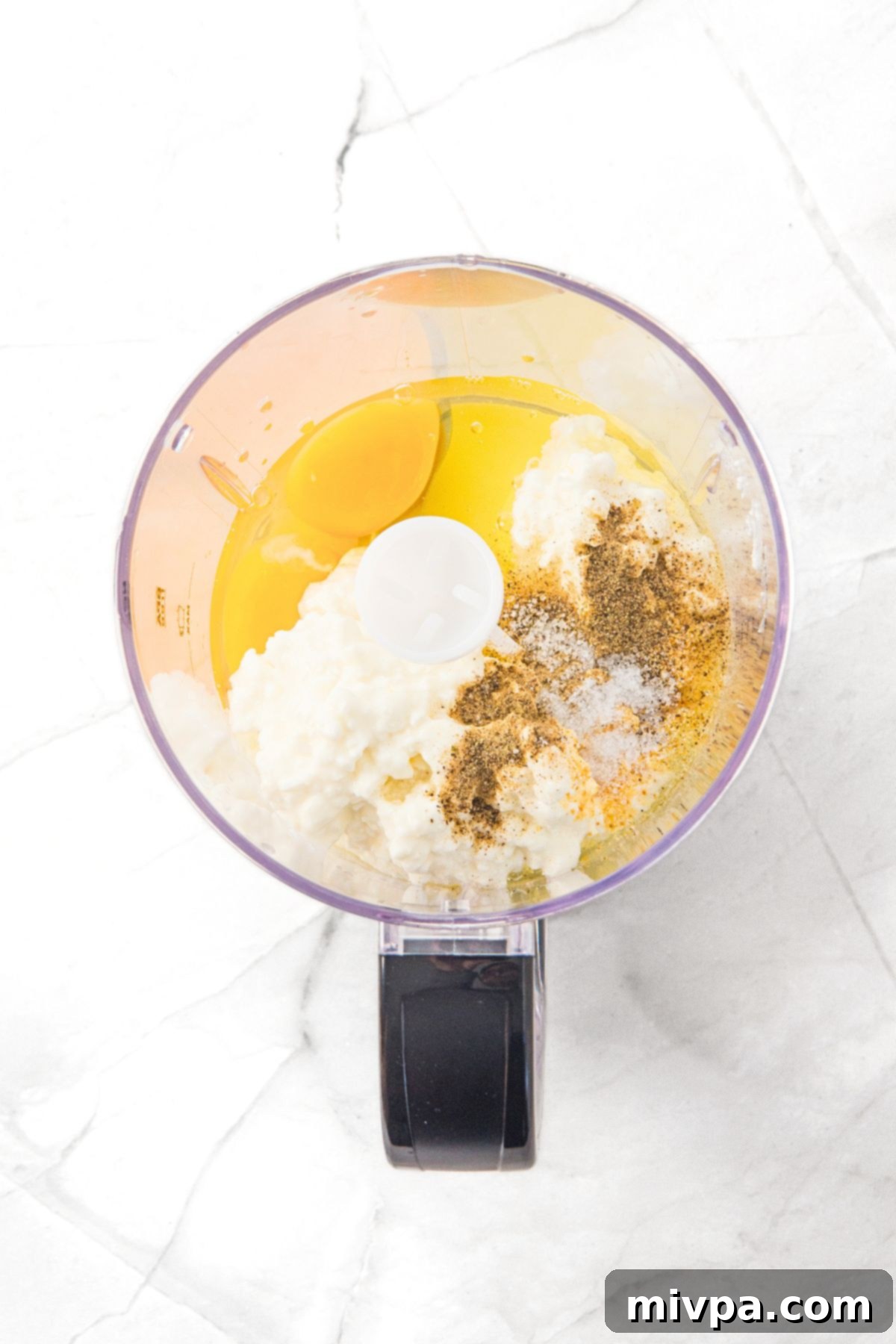 Viral Cottage Cheese Flatbread Eggs, cottage cheese and condiments in bowl of food processor.