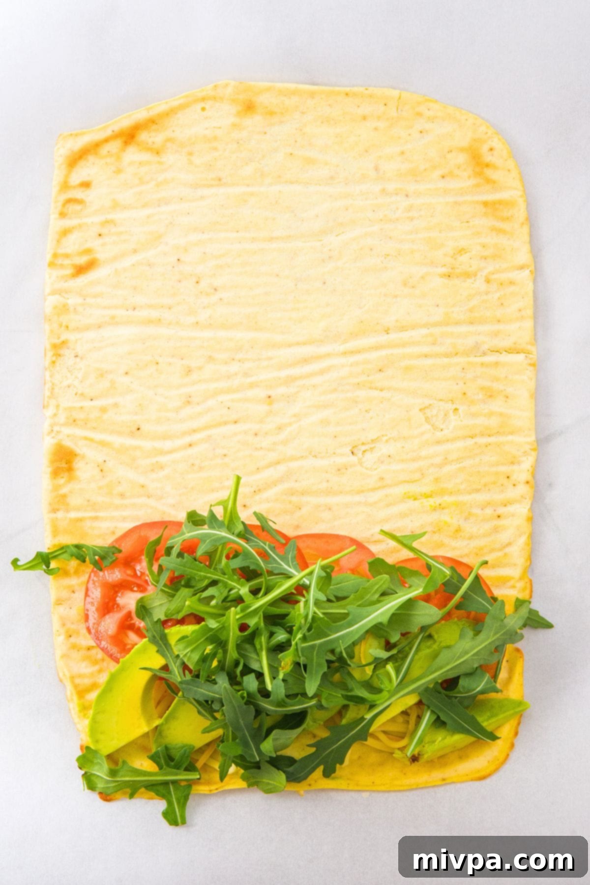 Gluten-Free Cottage Cheese Flatbread Tomato slices, avocado slices and fresh arugula leaves on cottage cheese flatbread.