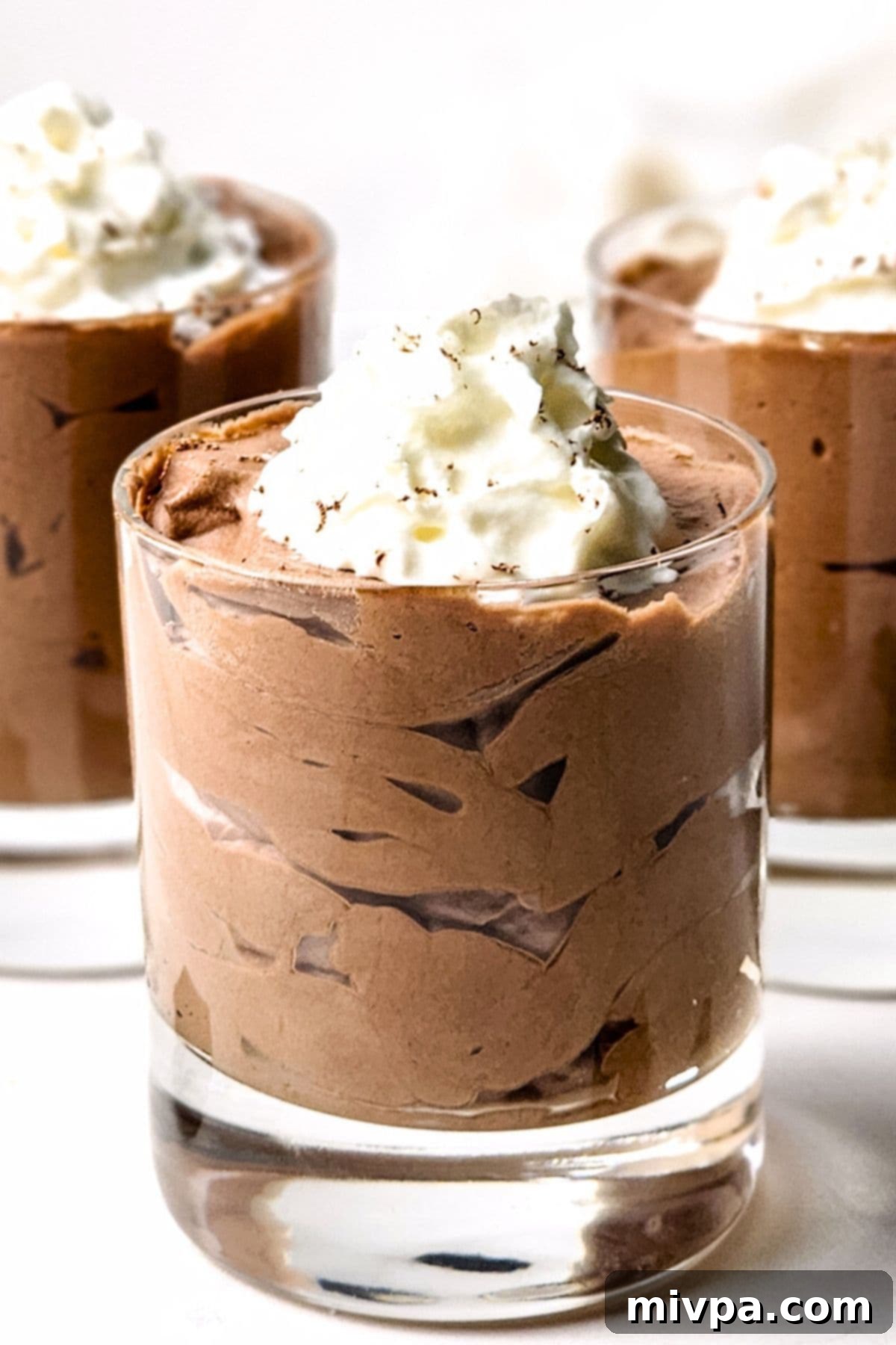 Glasses of chocolate dessert topped with whipped cream