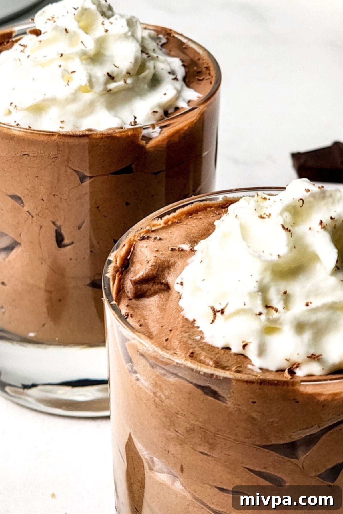 Up close view of gluten-free chocolate mousse topped with whipped cream.
