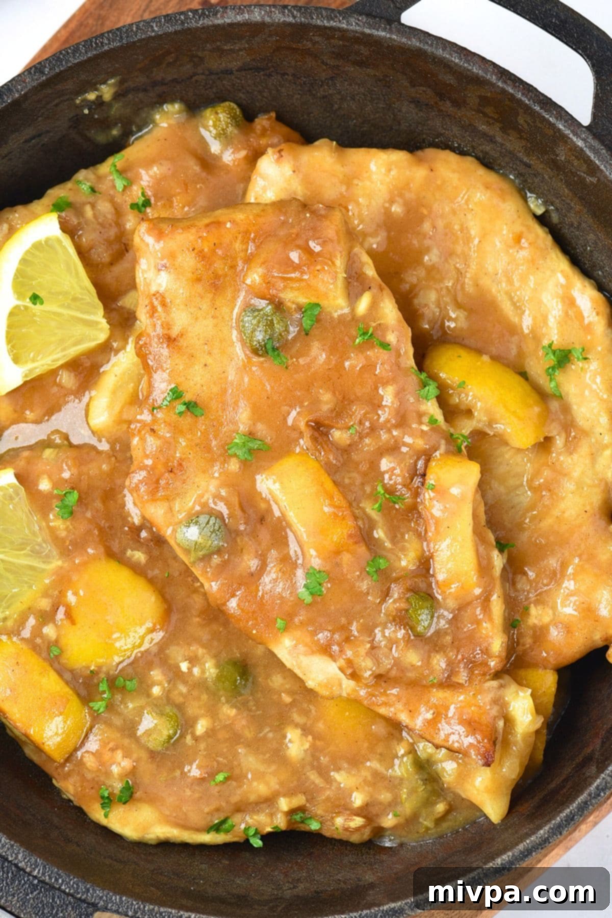 A skillet with lemon chicken piccata.