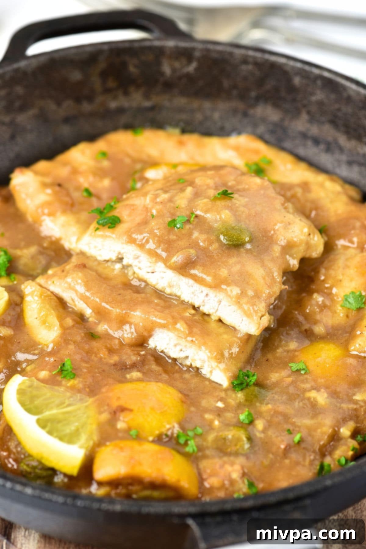 Half-eaten lemon chicken piccata garnished with chopped parsley