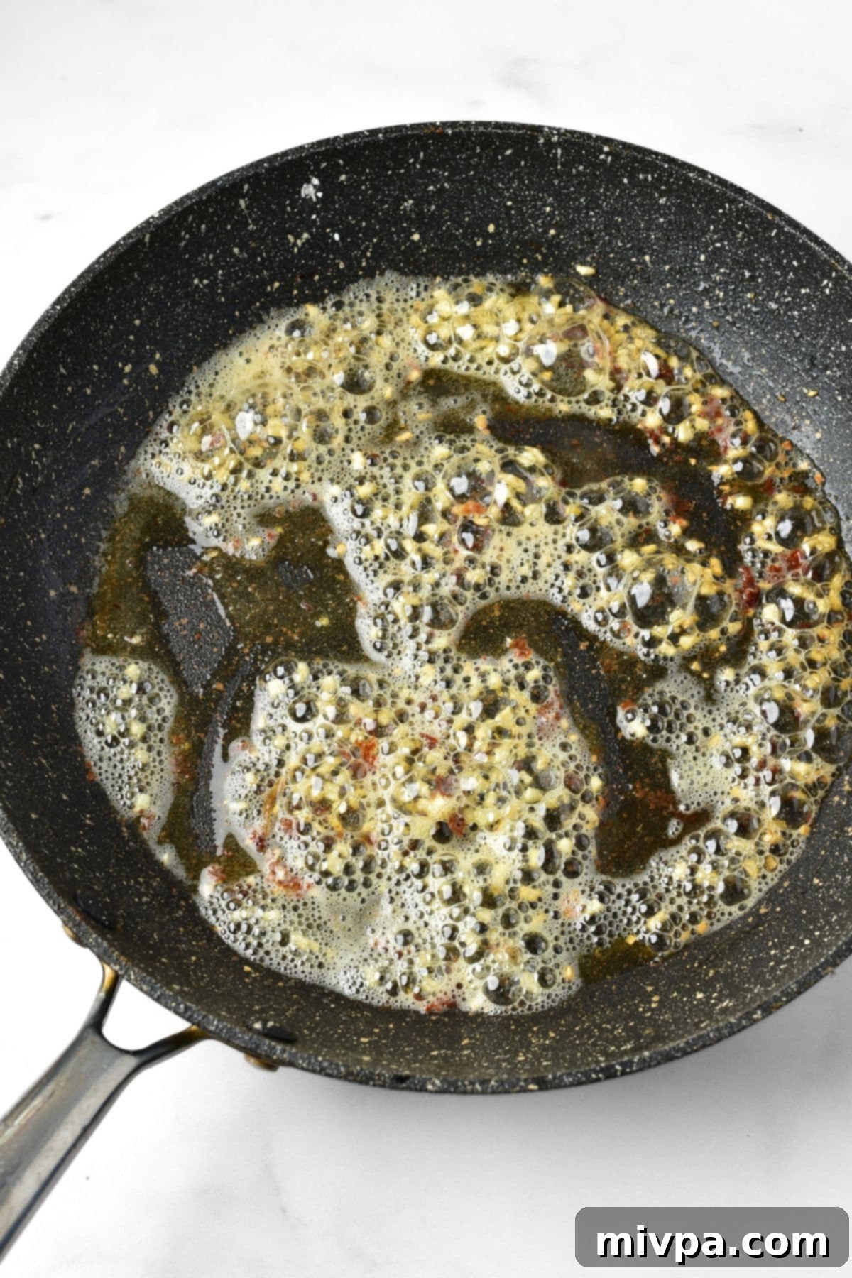 Sautéing freshly minced garlic in the same skillet after searing the chicken.