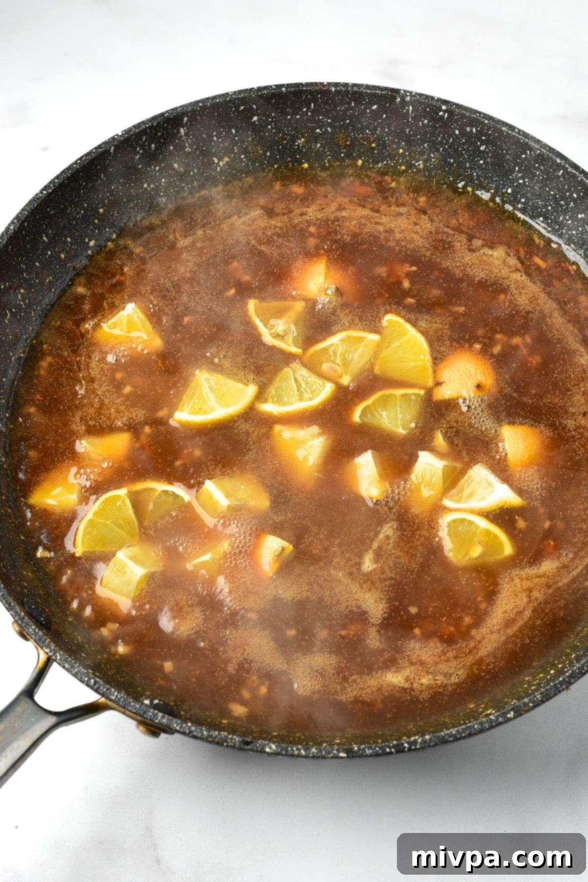 Cooking lemon slices in an orange brown liquid in skillet