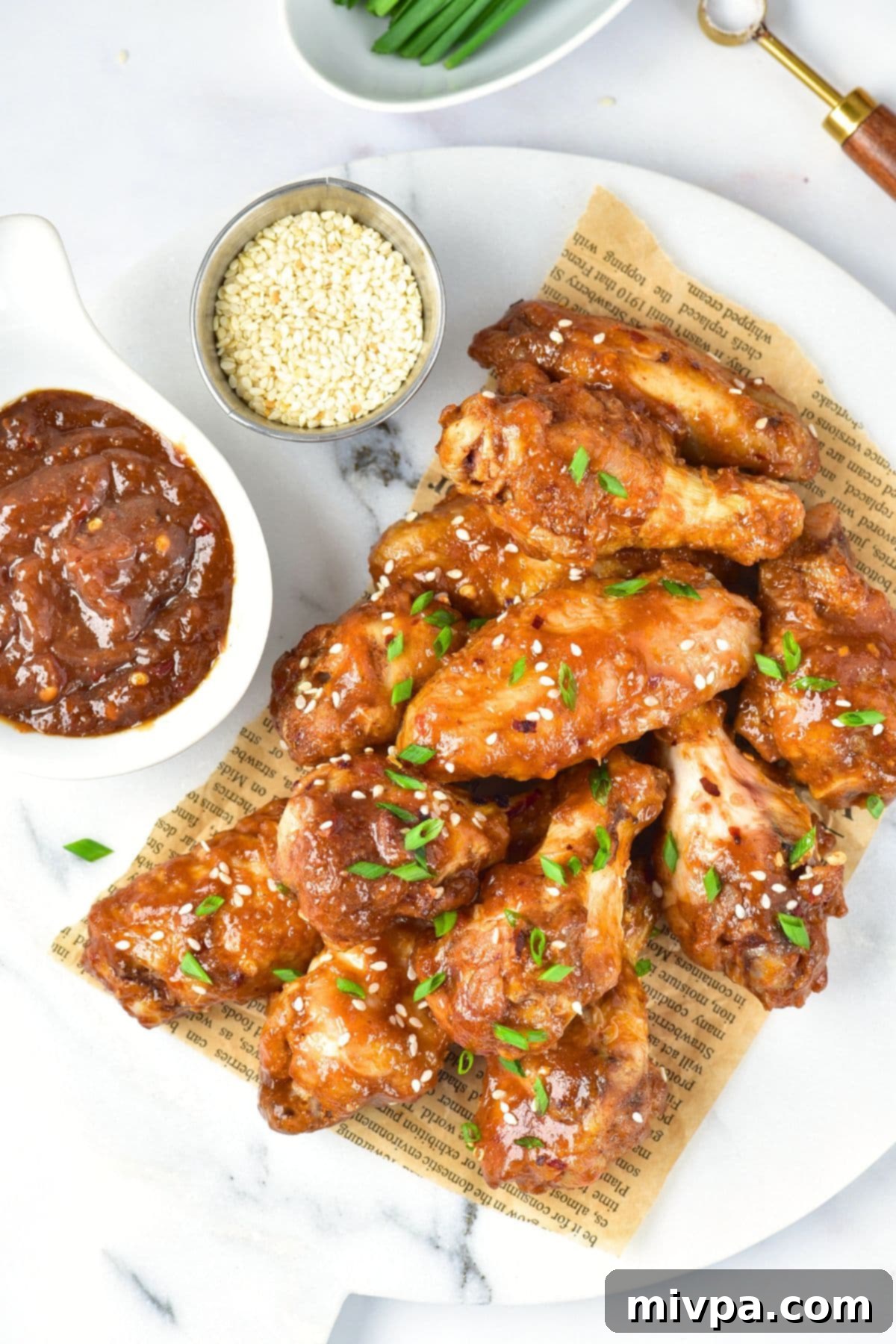 Top down view of beautifully garnished Asian sticky wings on a marble board, ready to be served.