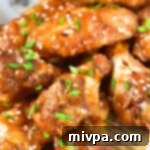 Sticking chicken wings garnished with spring onions and sesame seeds, piled high on a plate.