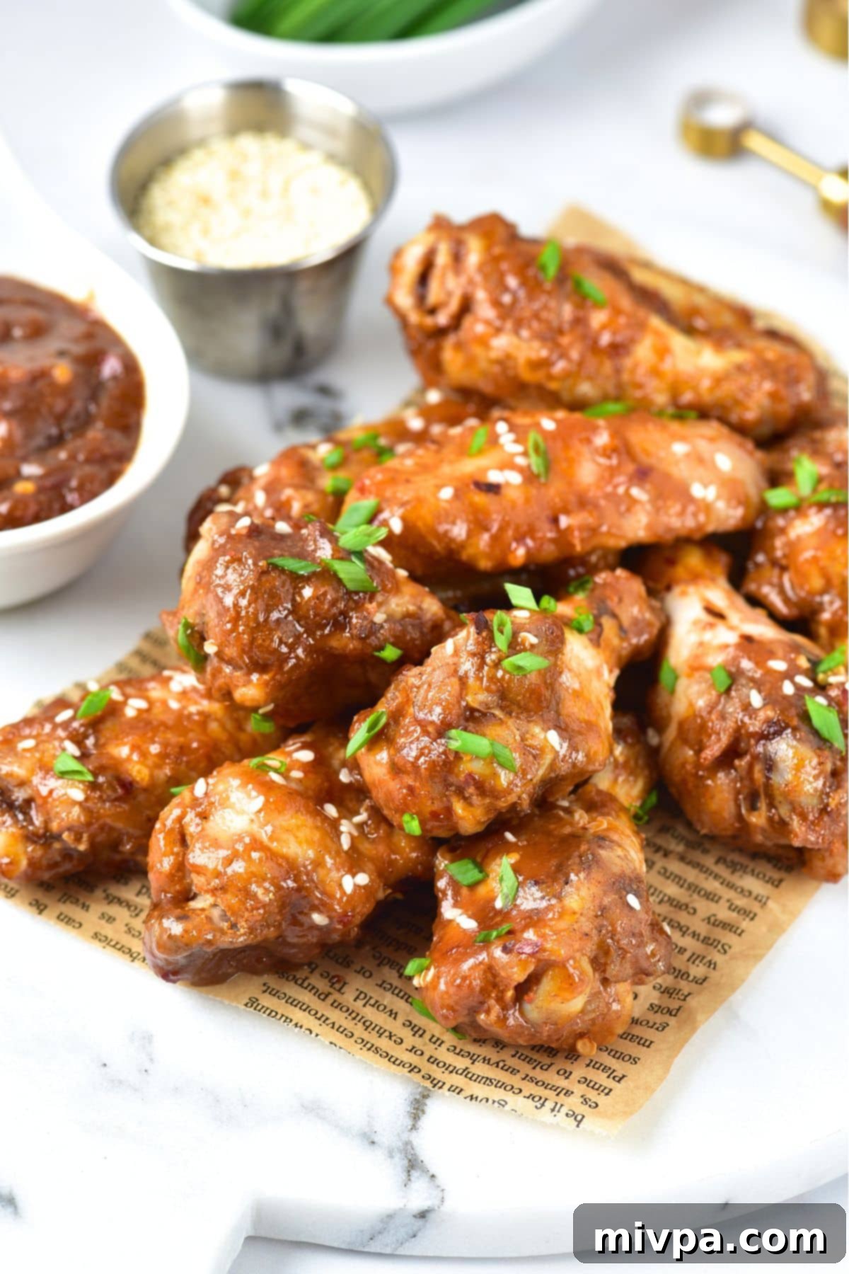 Asian sticky chicken wings on parchment-lined marble board, close up.