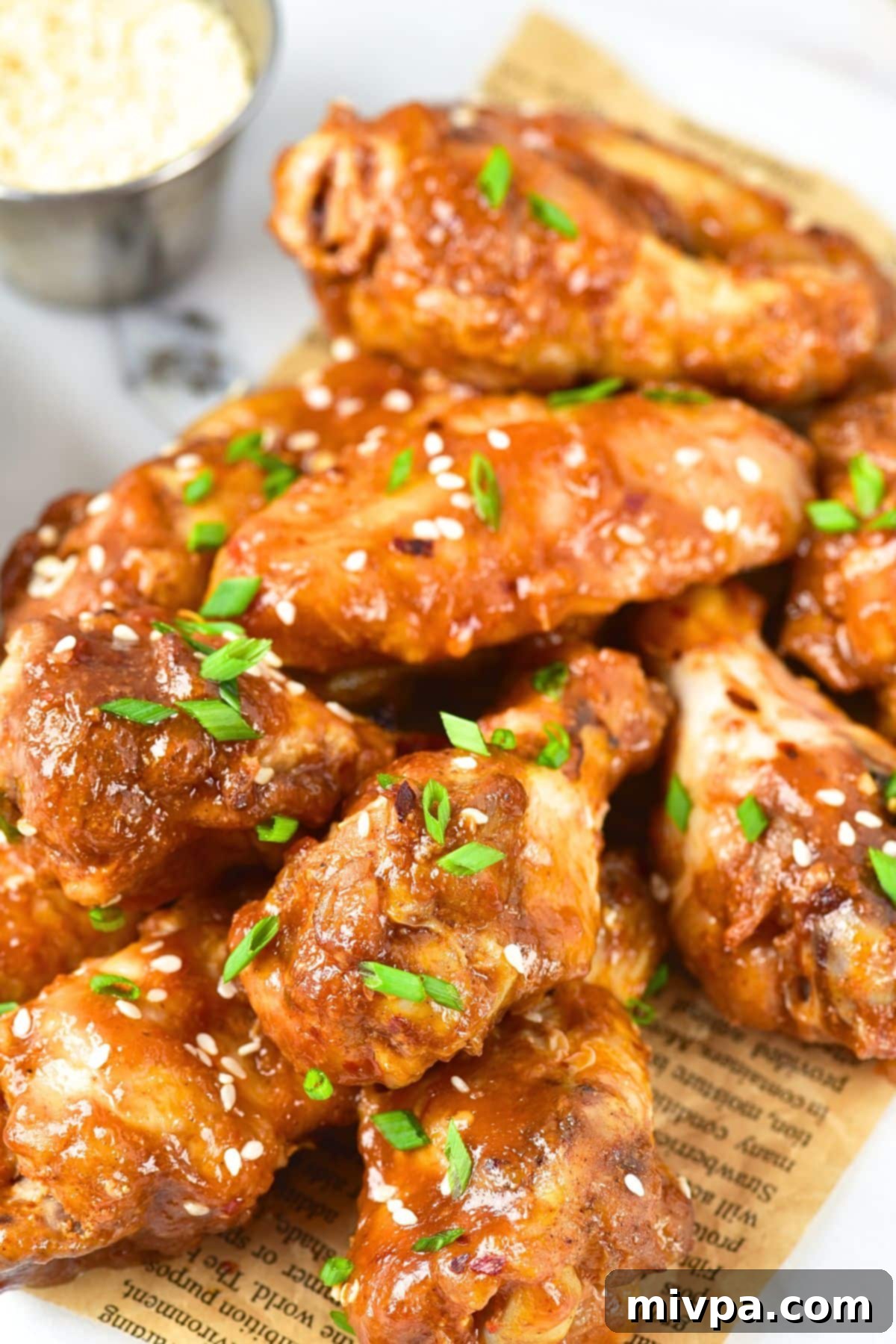 Up close view of sticky baked chicken wings sprinkled with green onions and sesame seeds.
