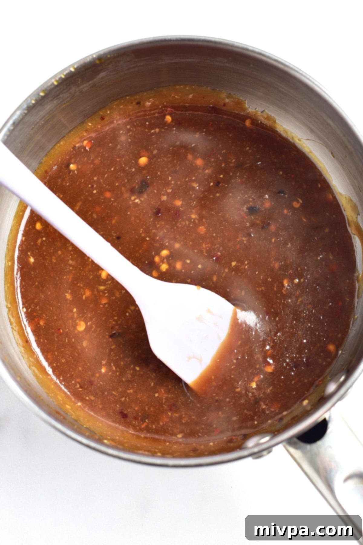 Cooking brown sauce in a saucepan, visibly thickening after adding cornstarch slurry.