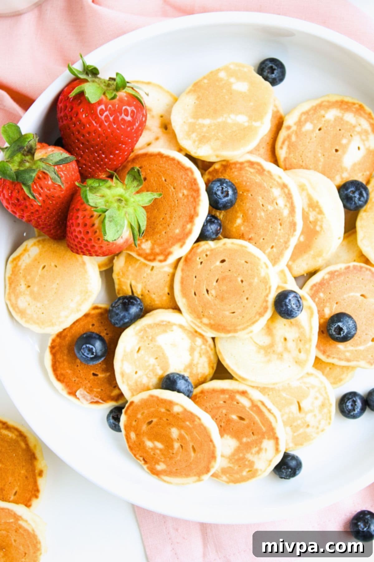Up close view of a plate of gluten-free mini pancakes and fresh berries