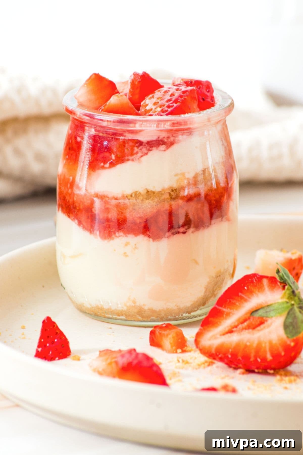 Strawberry Cheesecake Cups (Gluten-Free, No-Bake) A strawberry cheesecake cup on plate.