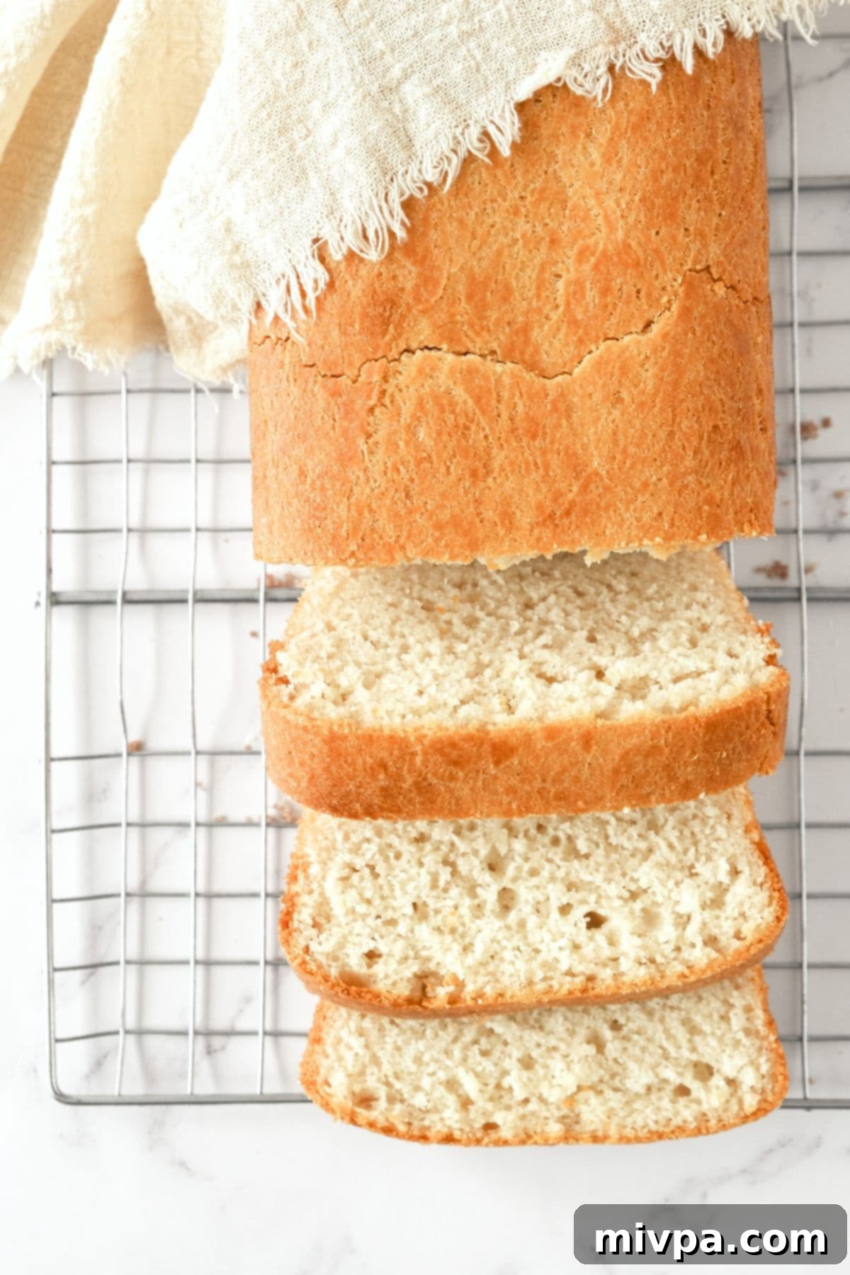 Half-sliced loaf of egg-free gluten-free bread on wire rack.