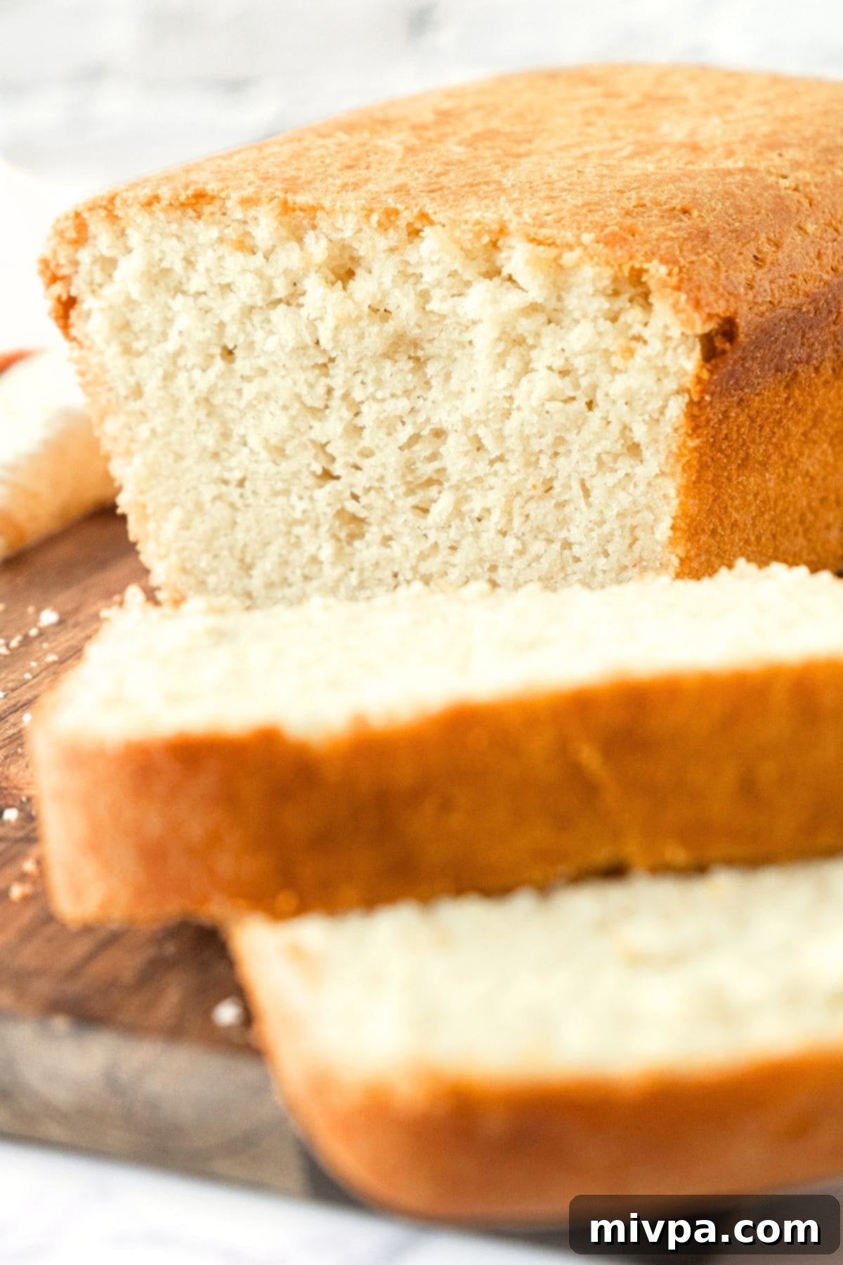 Half-sliced loaf of gluten-free egg-free bread on wooden board.