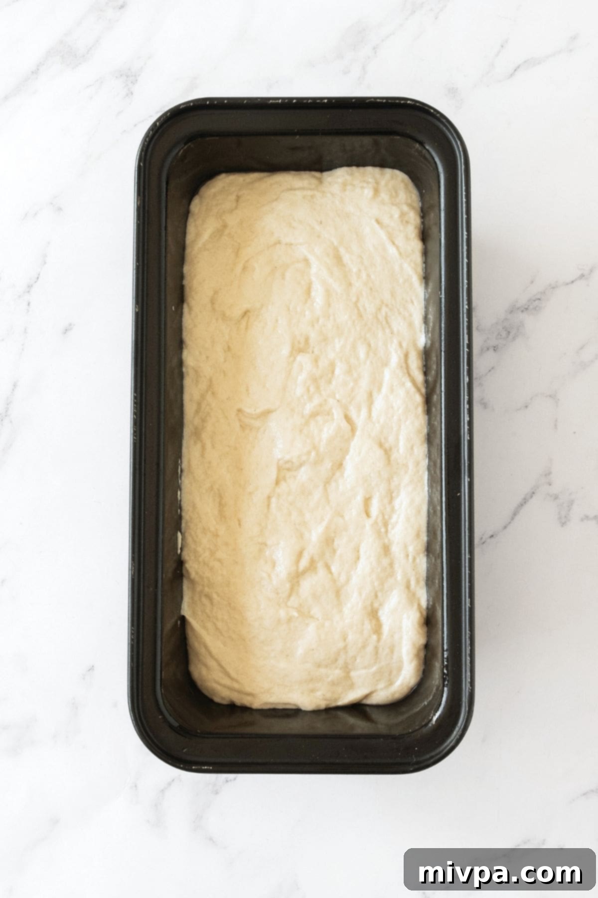Bread dough in metal loaf pan.