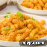 A plate of fusilli pasta garnished with basil leaves