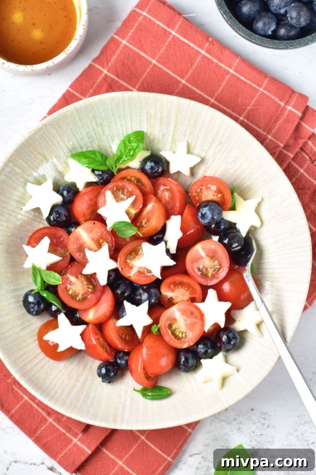 Caprese Salad with Blueberries A plate of caprese salad with blueberries on red towel