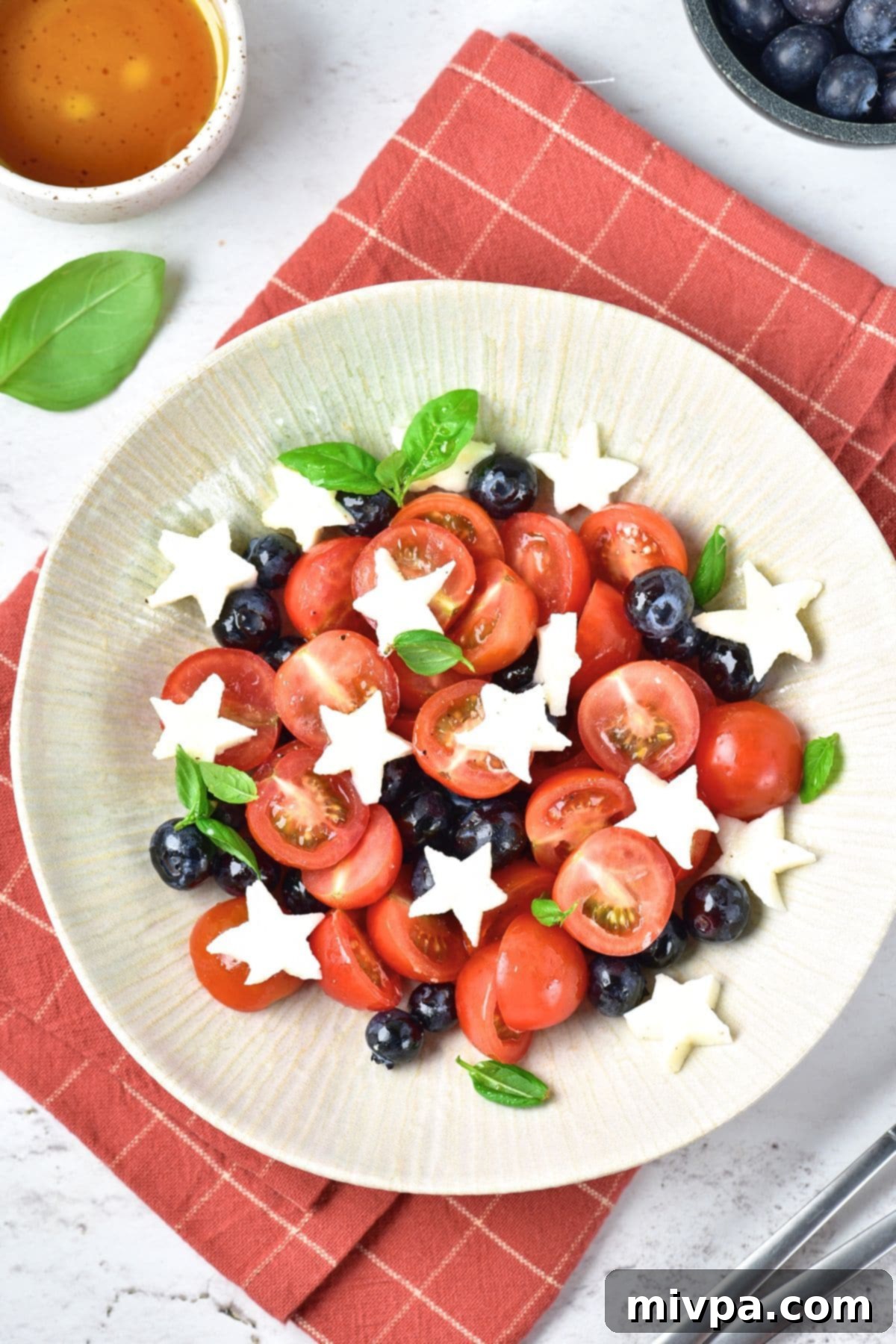Fourth of July Caprese Salad (Gluten-Free) A bowl of star shaped mozzarella, cherry tomatoes, and blueberries.