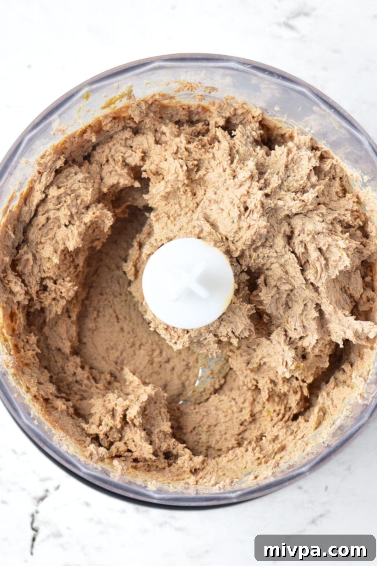 Homemade liver pate being blended to a smooth consistency in a food processor.