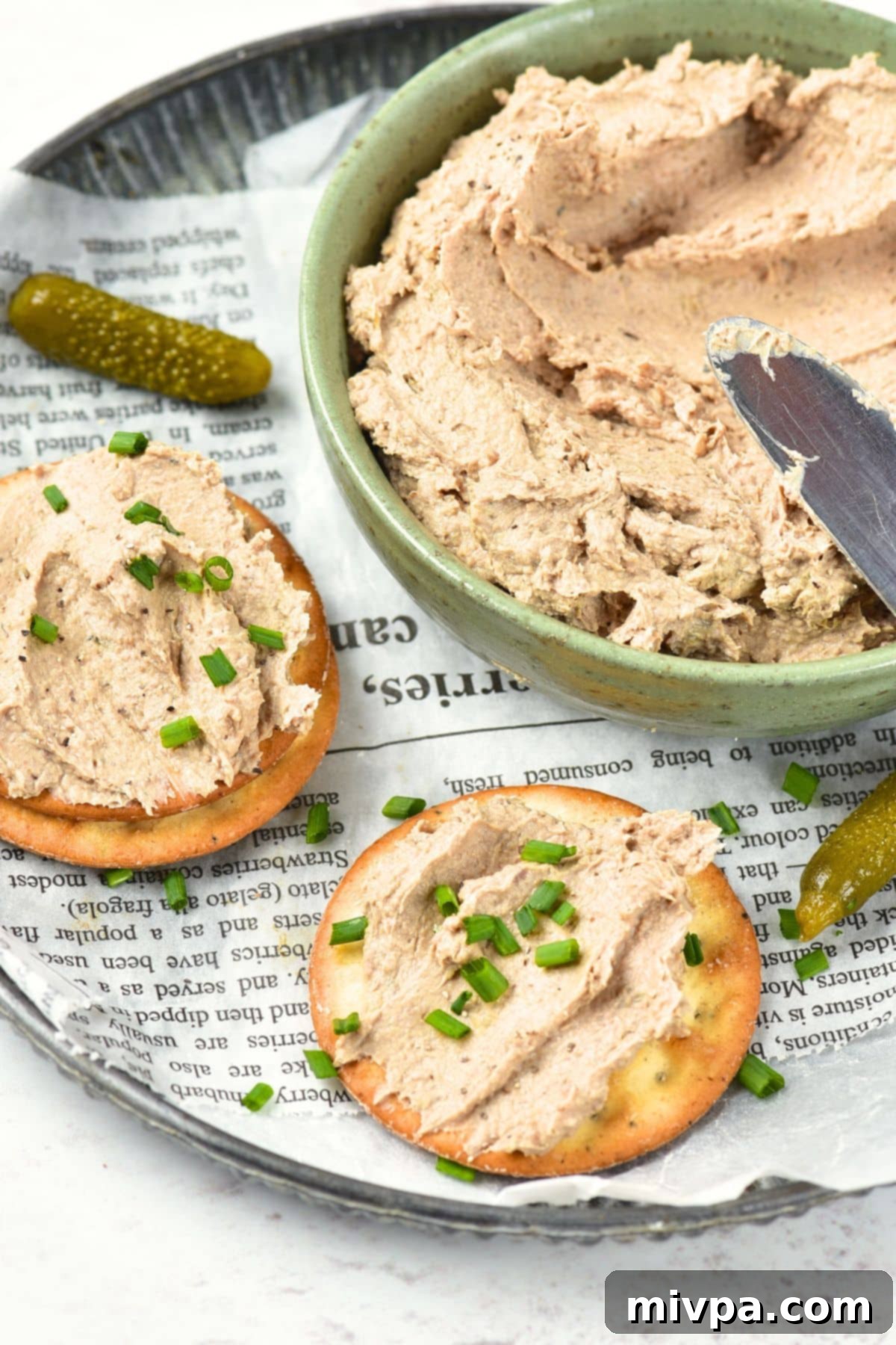 A cracker generously spread with homemade duck liver pate and garnished, symbolizing the final delicious outcome.