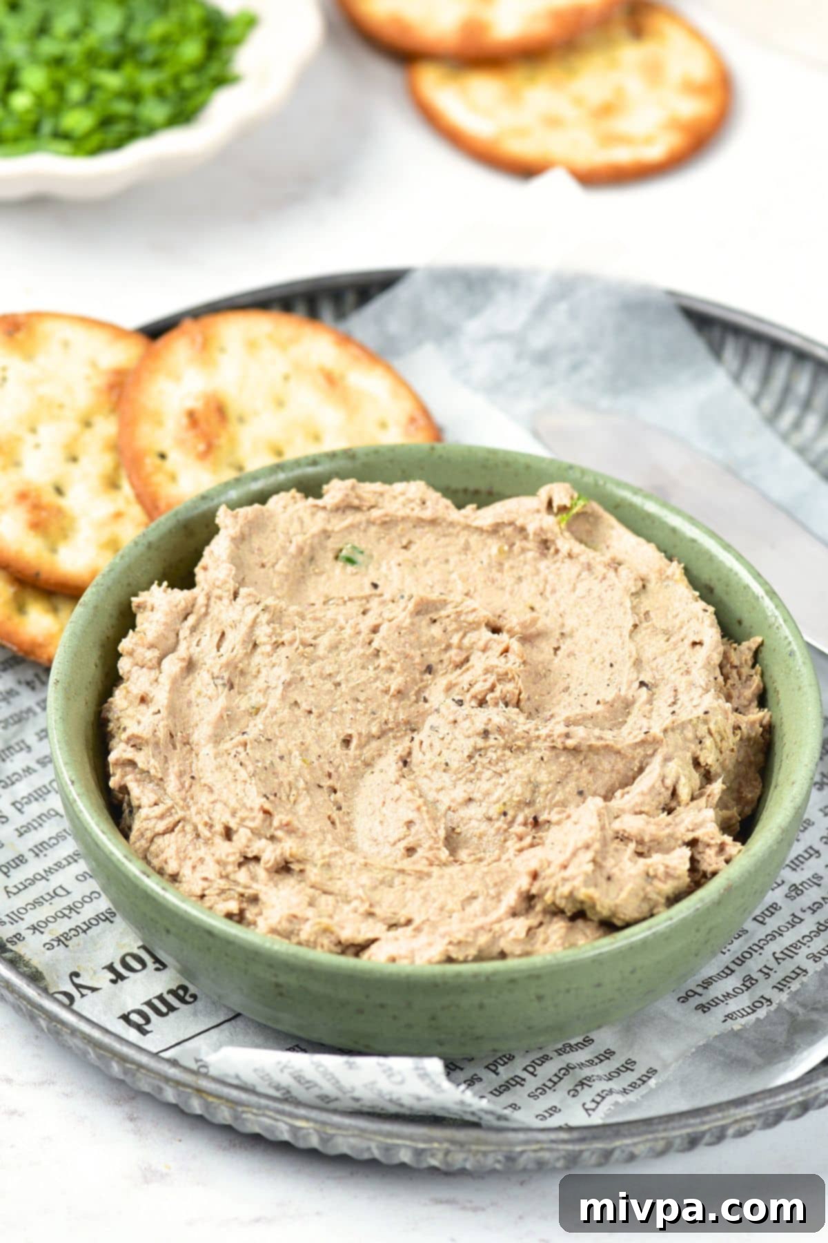A beautifully presented bowl of duck liver pate, garnished and ready for serving on a tray.
