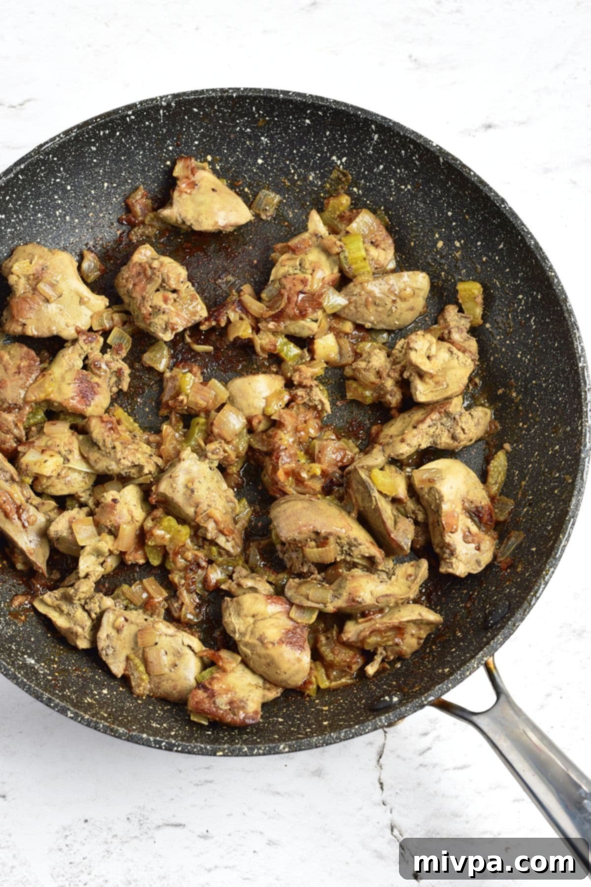 Cooked liver and vegetables, seasoned and ready for the next step, resting in a skillet.