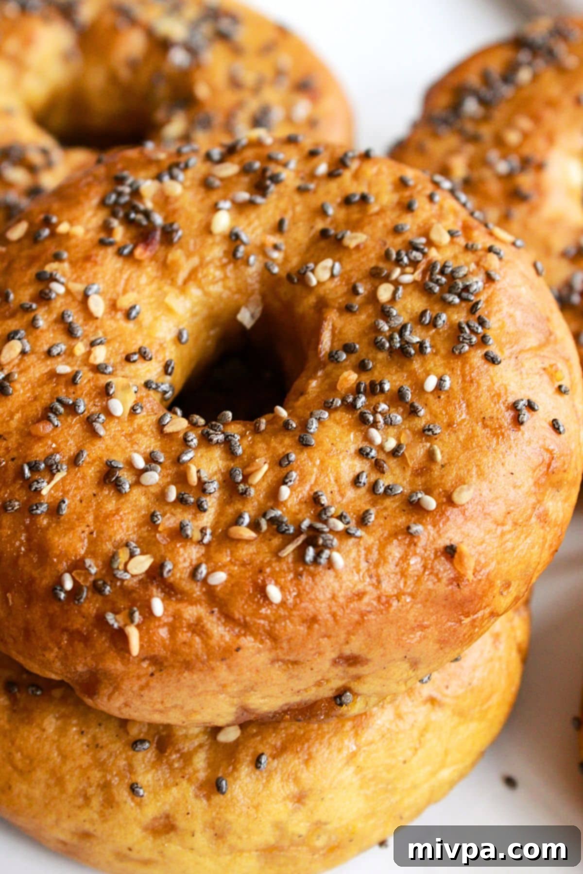 Gluten-Free Vegan Everything Bagels (Chewy and Tender!) A stack of golden brown, gluten-free vegan bagels topped with everything bagel seasoning, ready to be enjoyed.