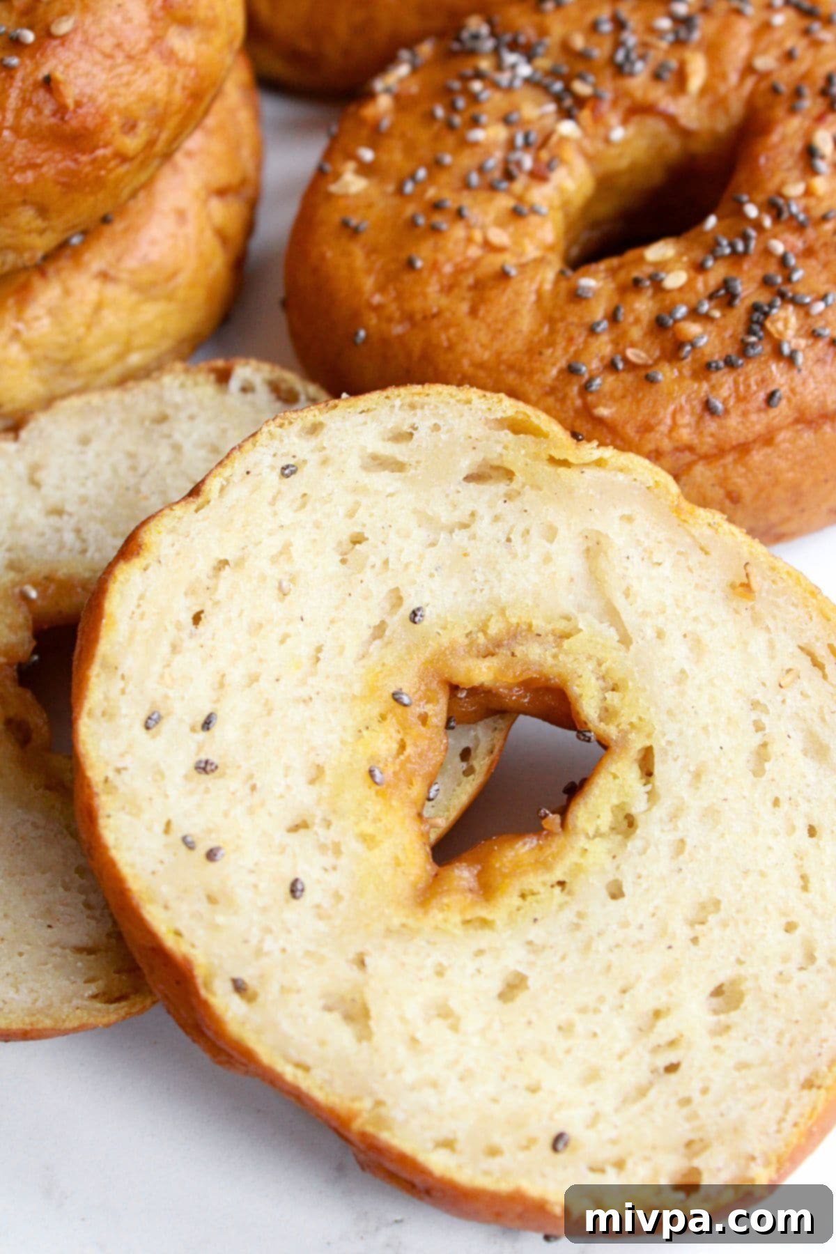 Vegan and Gluten-Free Bagels Close-up of freshly sliced vegan and gluten-free bagels on a clean white board, showcasing their tender interior.