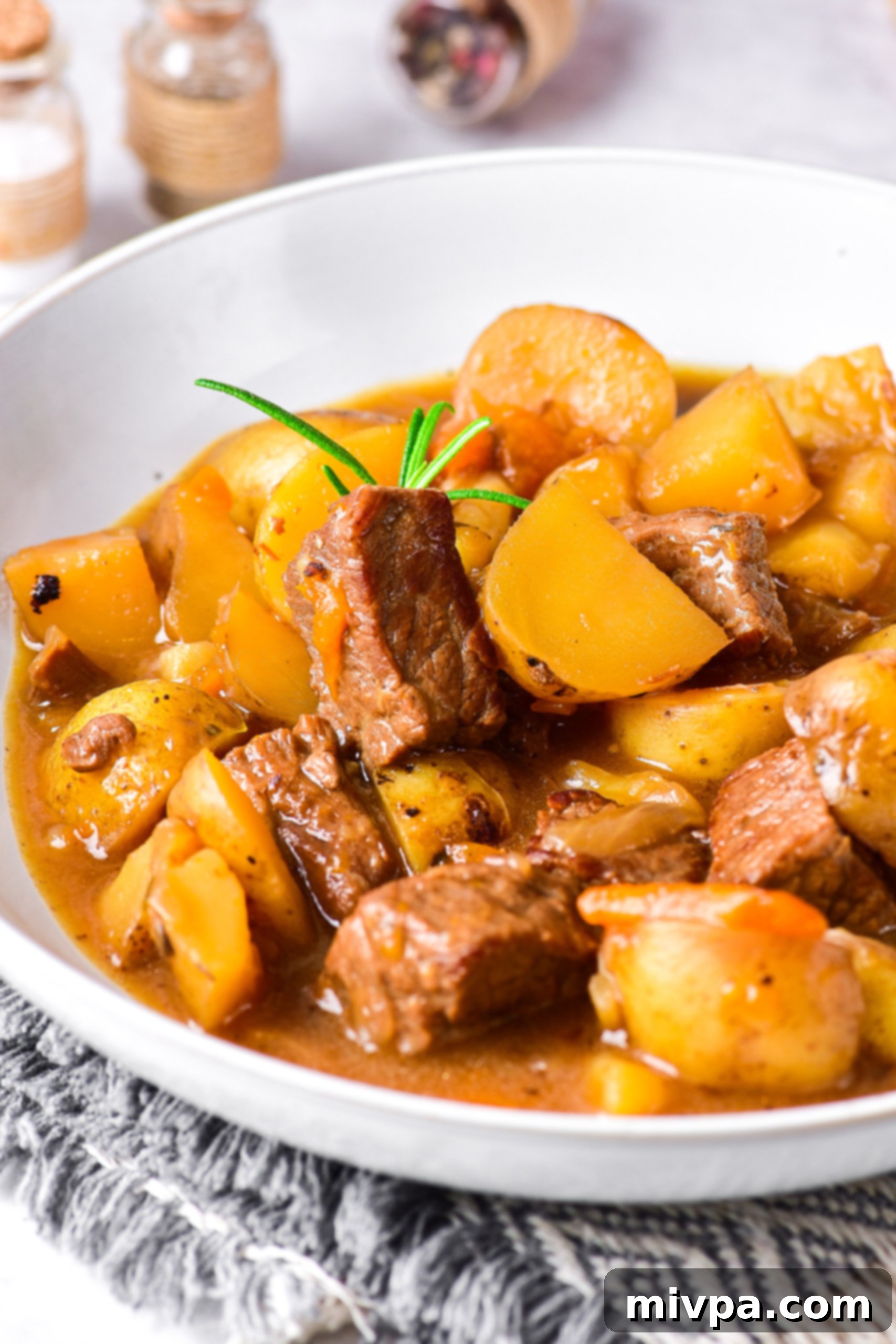 Easy Gluten Free Beef Stew (Dairy-Free) Up close shot of gluten-free beef stew on kitchen towel.