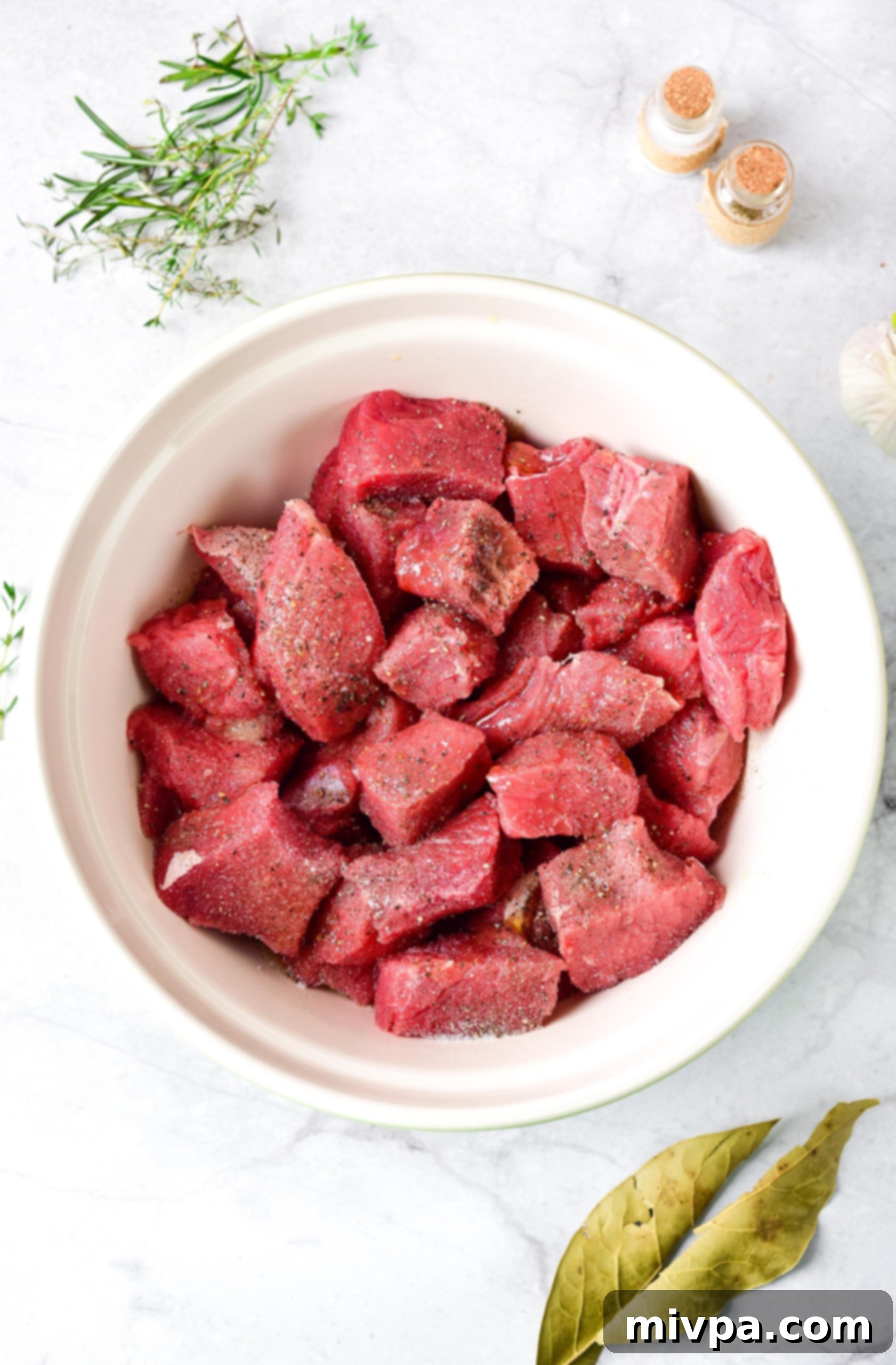 GF Beef Stew Recipe (Dairy-Free) Seasoned beef cubes in a white bowl.