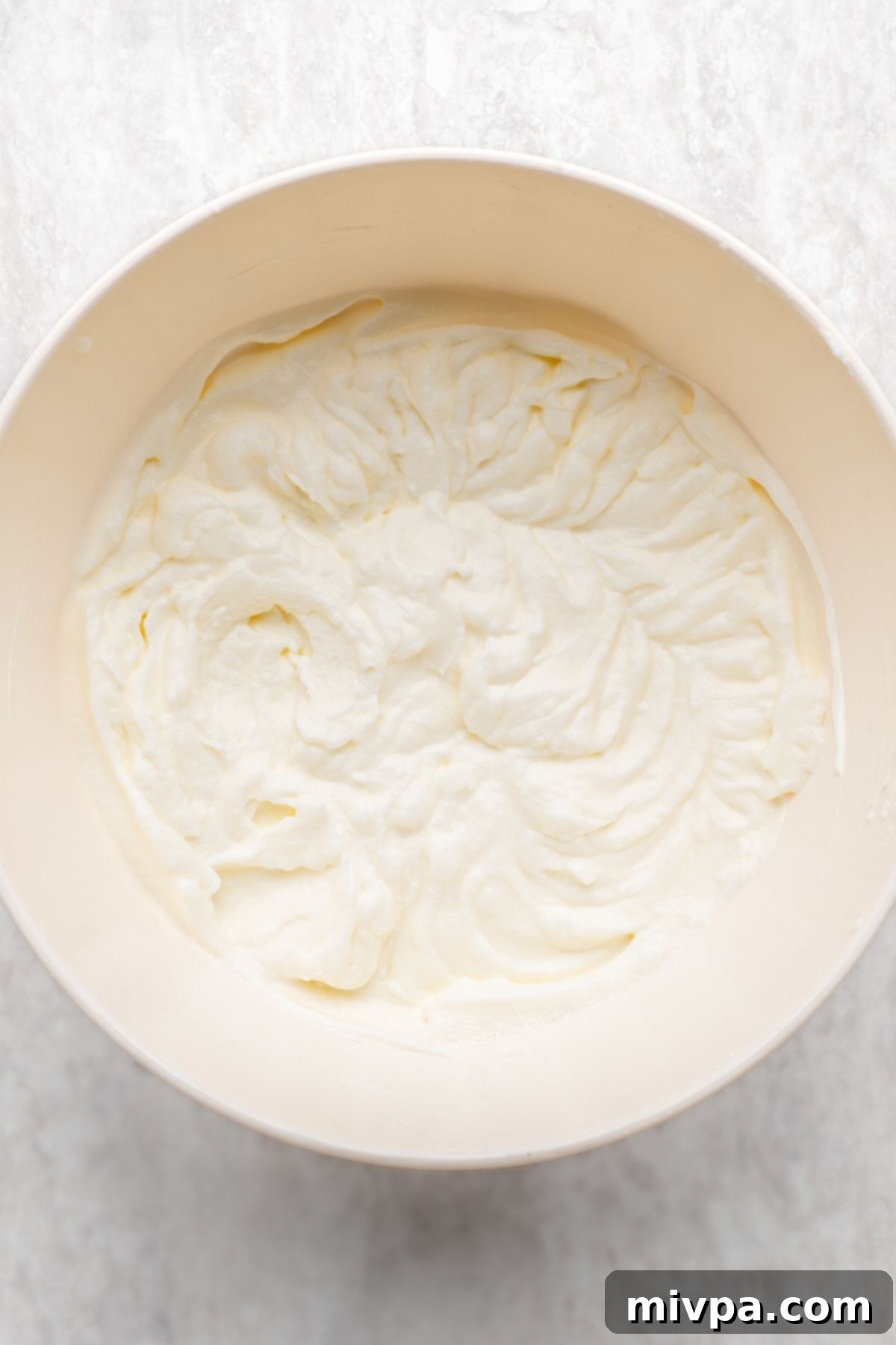 A fluffy bowl of freshly prepared whipped cream, perfectly aerated and ready to be used as a topping.