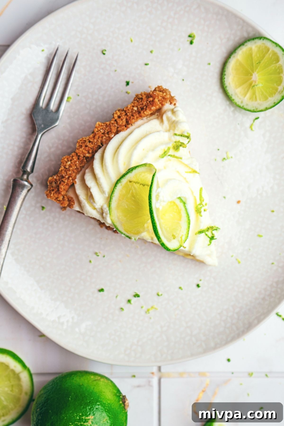 A pristine slice of gluten-free key lime pie, perfectly cut and ready to be enjoyed, highlighting its smooth filling and robust crust.
